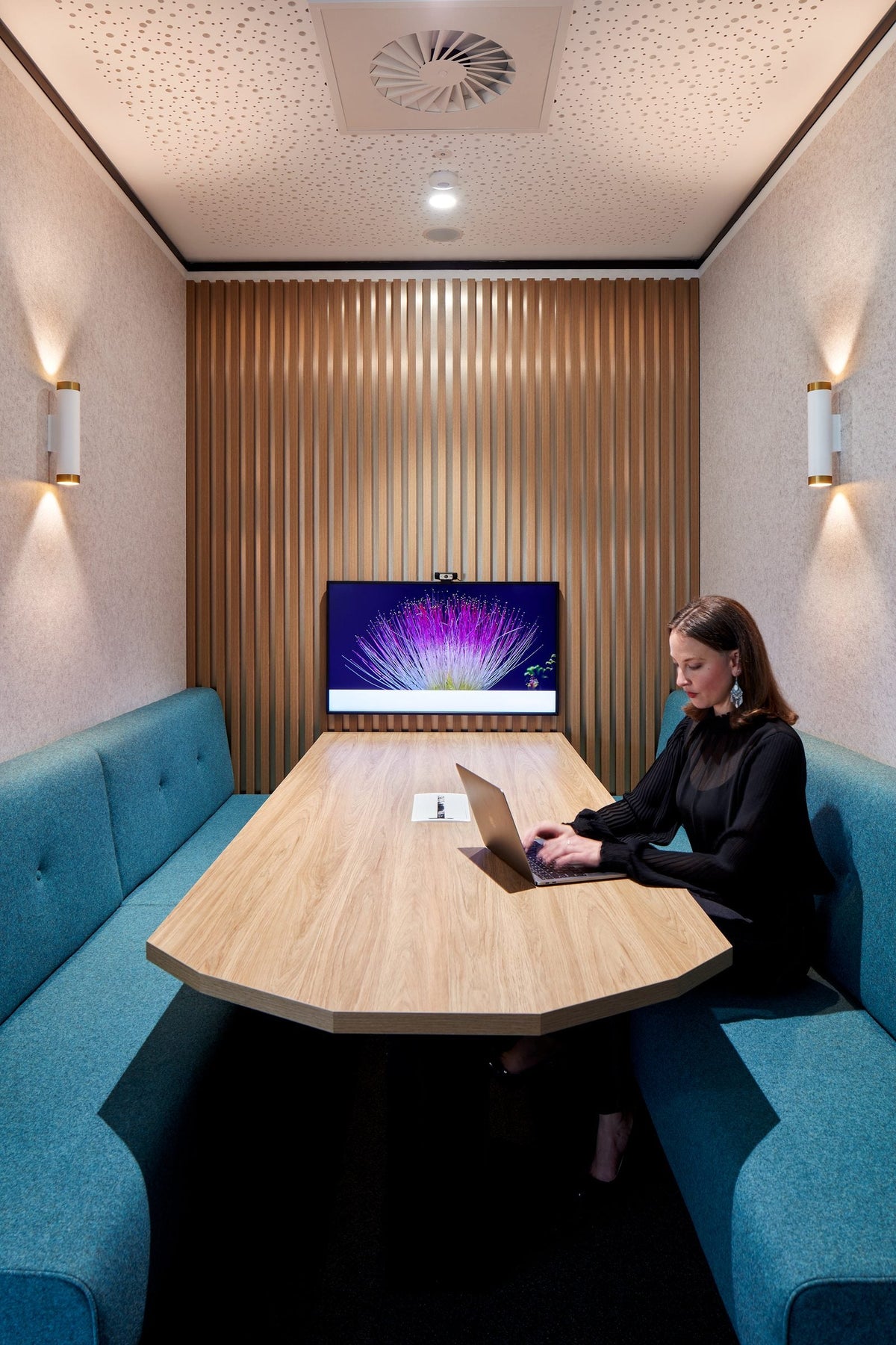 Person working in an enclosed booth with a curved table and screen