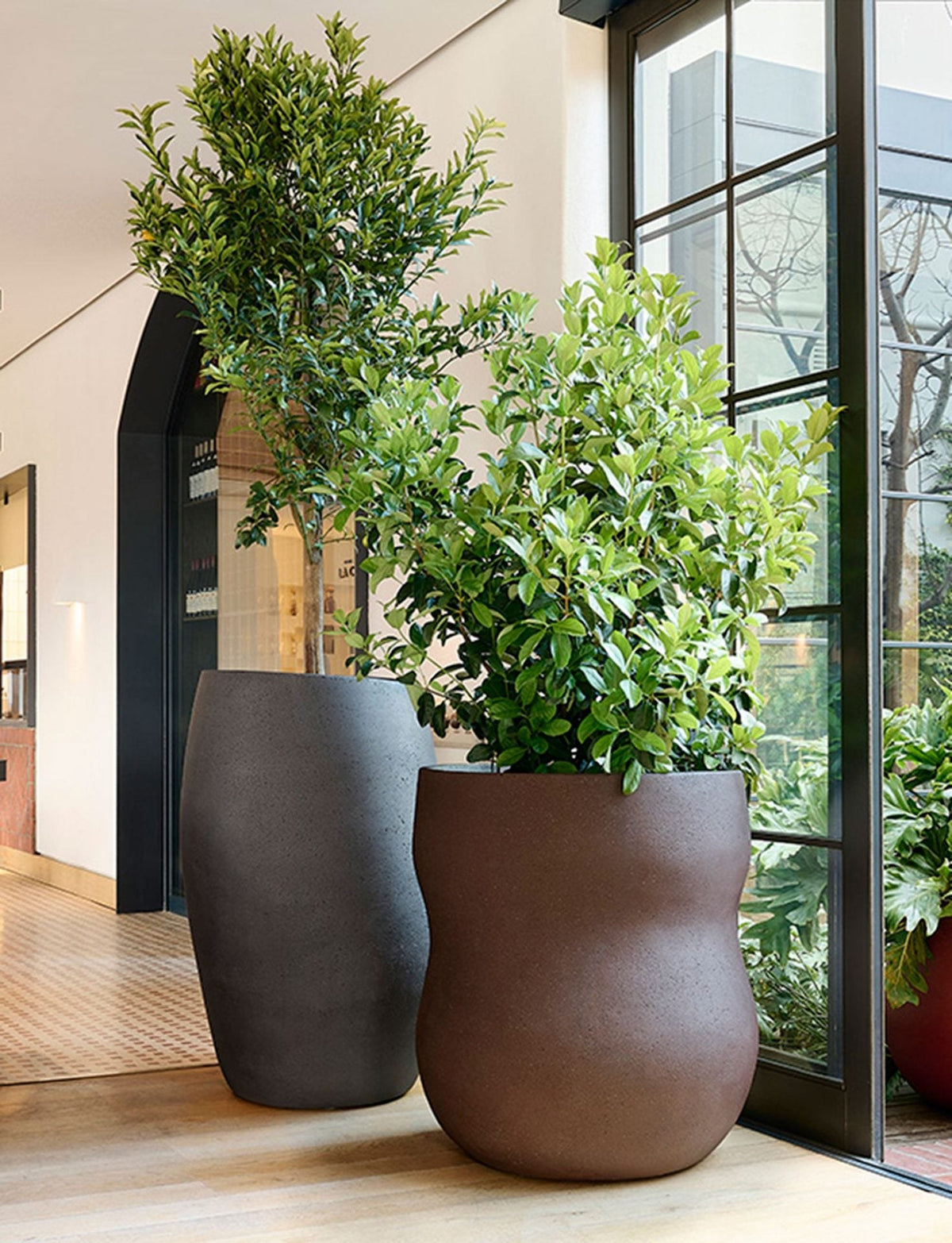 Indigenus Pebble planters in charcoal and earth tones beside a glazed entry